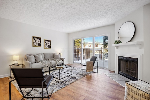 living room with a tile fireplace, a textured ceiling, and hardwood / wood-style floors