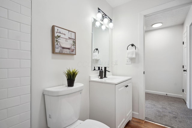 bathroom with a textured ceiling, toilet, and vanity