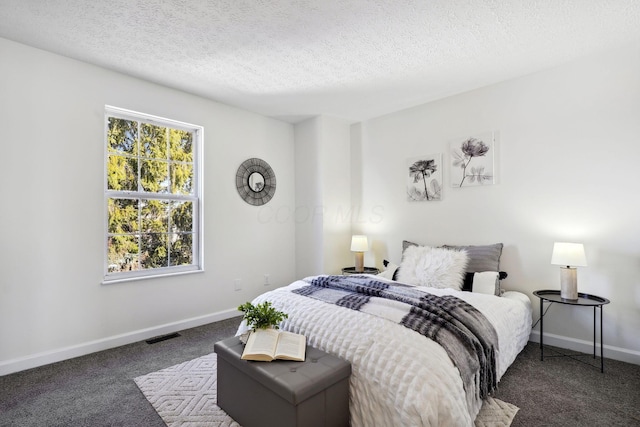 bedroom featuring a textured ceiling and dark colored carpet