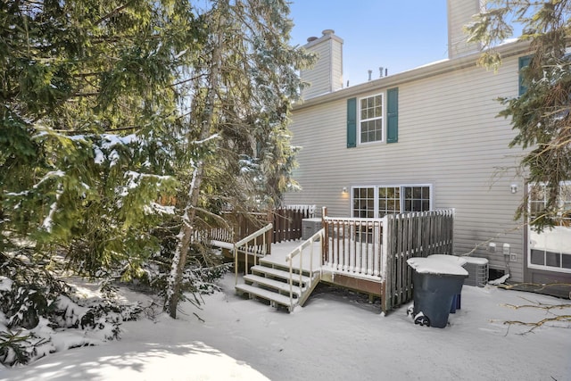 snow covered back of property with central air condition unit and a deck