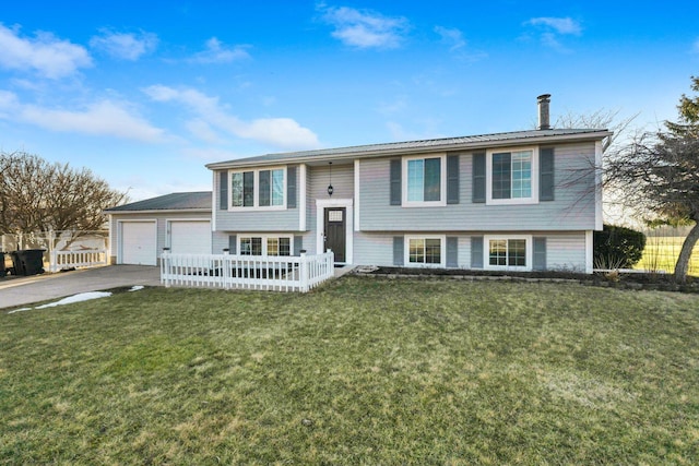 raised ranch with a garage, aphalt driveway, a front yard, and fence