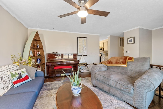 living room with crown molding, a textured ceiling, a ceiling fan, and wood finished floors