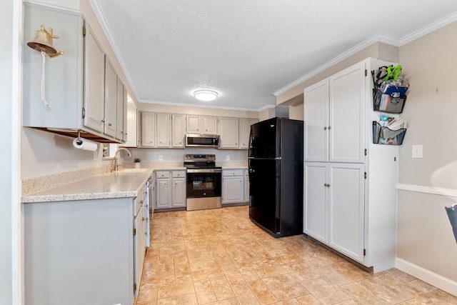 kitchen featuring appliances with stainless steel finishes, ornamental molding, a sink, a textured ceiling, and baseboards