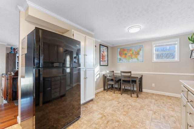 kitchen featuring a textured ceiling, ornamental molding, freestanding refrigerator, and white cabinetry