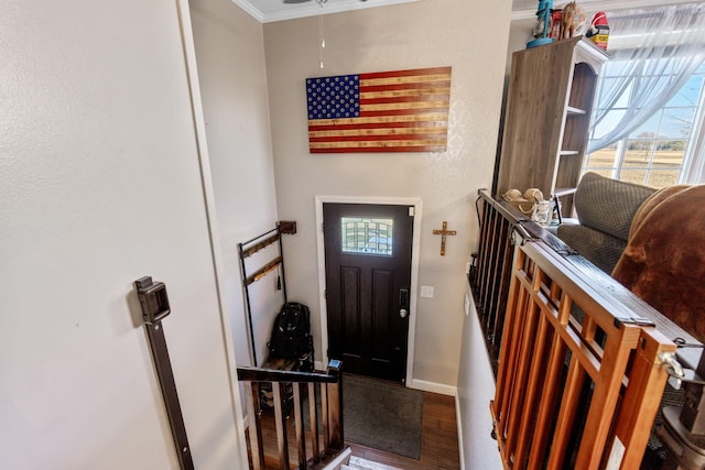 foyer featuring ornamental molding, wood finished floors, and baseboards