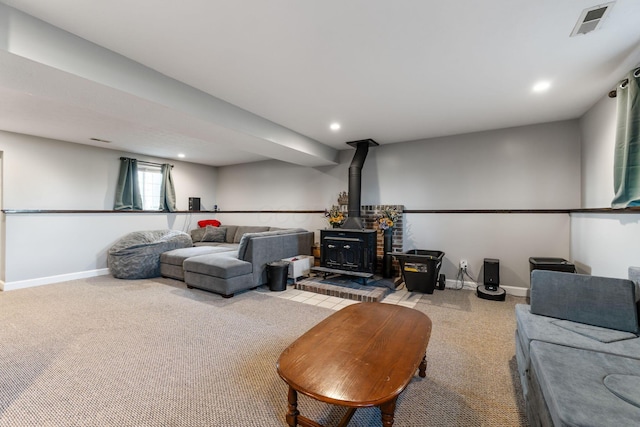 carpeted living room featuring a wood stove, visible vents, baseboards, and recessed lighting