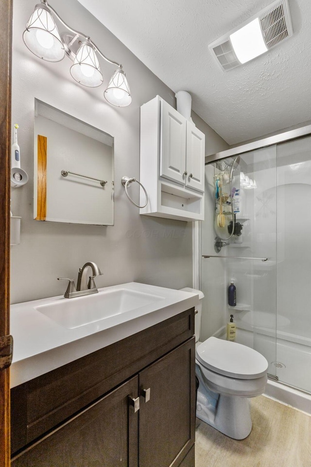 bathroom with visible vents, a shower stall, a textured ceiling, and wood finished floors