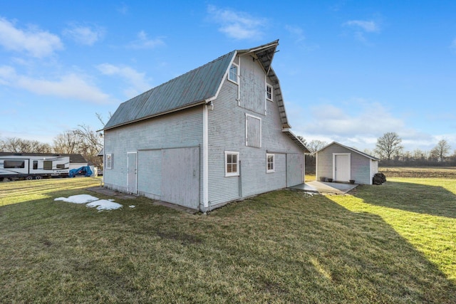 exterior space featuring an outbuilding, metal roof, a barn, a gambrel roof, and a lawn