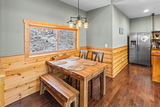 dining space featuring dark hardwood / wood-style flooring, a notable chandelier, and wood walls