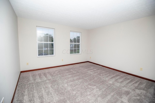 carpeted empty room featuring a textured ceiling