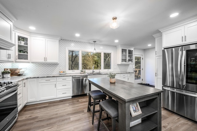 kitchen with stainless steel appliances, light stone countertops, and white cabinets