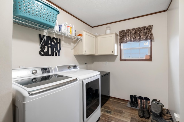 laundry area with dark wood-type flooring, cabinets, washer and dryer, a textured ceiling, and ornamental molding