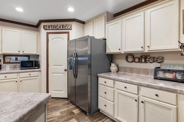 kitchen with stainless steel appliances, crown molding, cream cabinets, and dark hardwood / wood-style floors