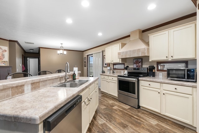 kitchen with appliances with stainless steel finishes, pendant lighting, sink, dark wood-type flooring, and custom range hood