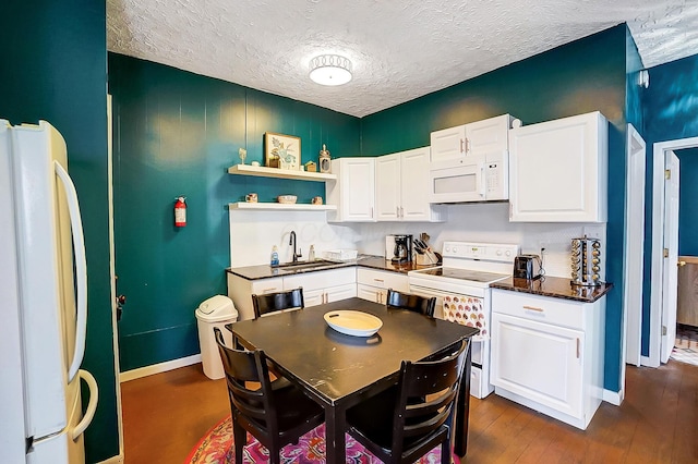 kitchen with dark hardwood / wood-style flooring, sink, white cabinets, and white appliances