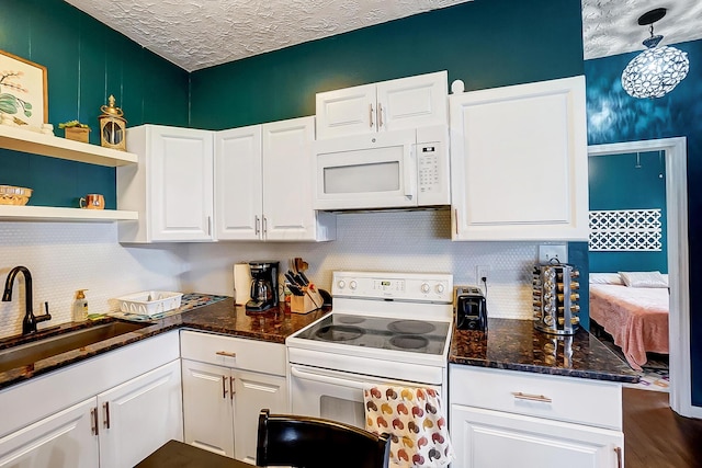 kitchen featuring white appliances, decorative light fixtures, and white cabinets