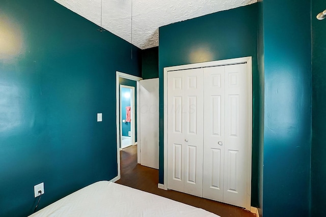bedroom featuring a closet, dark hardwood / wood-style floors, and a textured ceiling