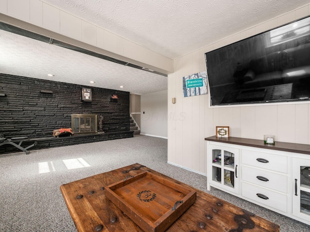 living area featuring baseboards, a fireplace, stairway, and a textured ceiling