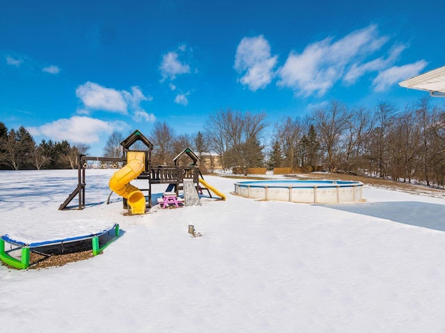 snow covered playground featuring a playground and an outdoor pool