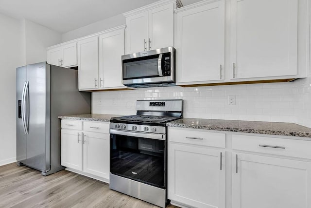 kitchen featuring white cabinets, light wood finished floors, dark stone counters, and stainless steel appliances
