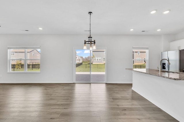 unfurnished living room featuring recessed lighting, a chandelier, wood finished floors, and baseboards