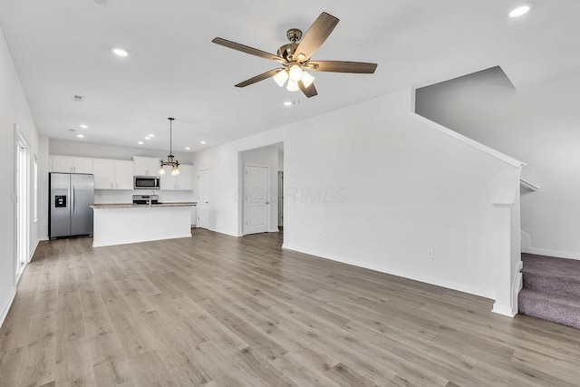 unfurnished living room featuring recessed lighting, stairway, light wood finished floors, and baseboards