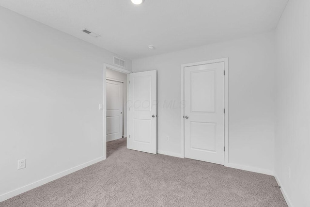 unfurnished bedroom featuring carpet floors, visible vents, and baseboards