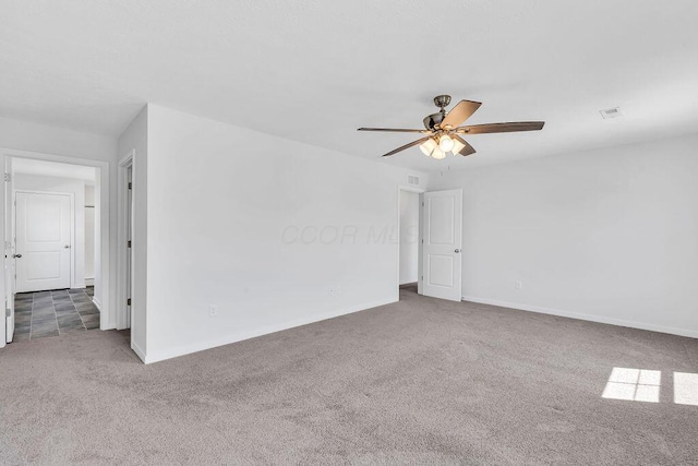 carpeted spare room with baseboards, a ceiling fan, and visible vents