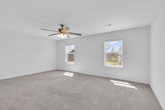 spare room featuring a healthy amount of sunlight, carpet flooring, baseboards, and visible vents