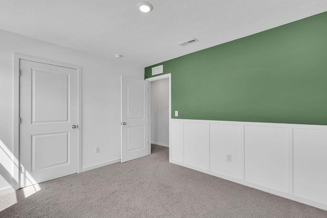 unfurnished bedroom with a textured ceiling, carpet, and visible vents