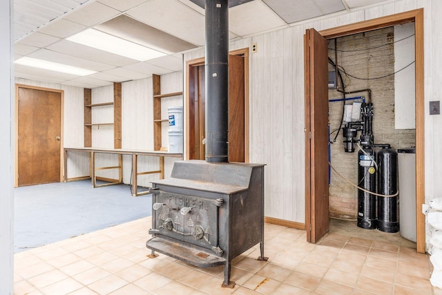 below grade area featuring wooden walls, a wood stove, and a paneled ceiling