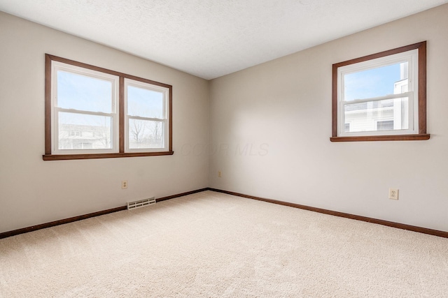 empty room featuring baseboards, carpet, visible vents, and a textured ceiling