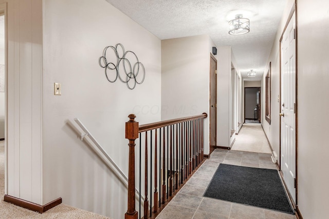 hall with an upstairs landing, a textured ceiling, and baseboards