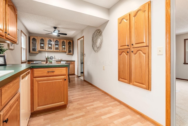 kitchen with glass insert cabinets, white dishwasher, light wood finished floors, and baseboards