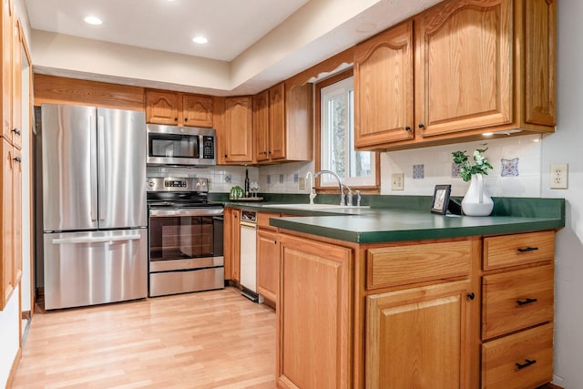 kitchen with a sink, tasteful backsplash, dark countertops, and appliances with stainless steel finishes