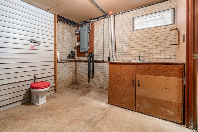 interior space featuring electric panel, brick wall, and a sink