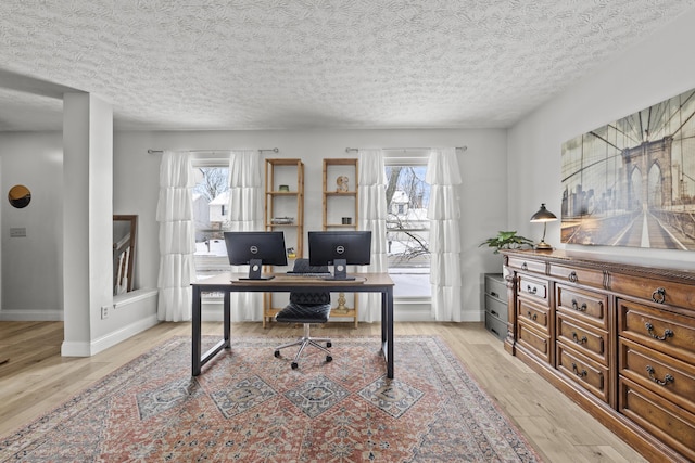 home office featuring a textured ceiling, light wood-type flooring, and baseboards