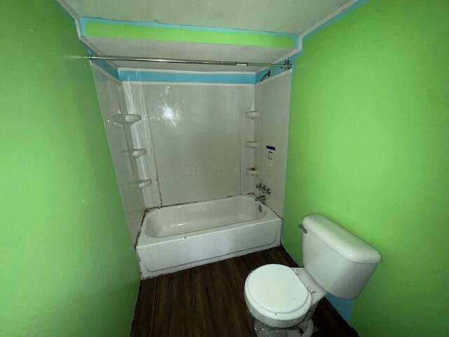 bathroom featuring wood-type flooring, shower / bathtub combination, and toilet