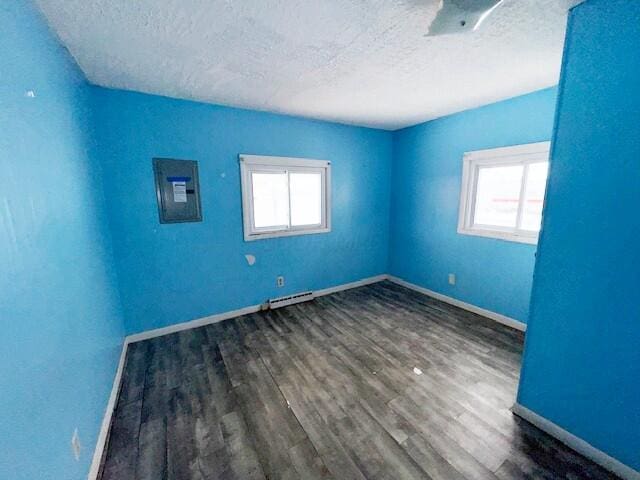 unfurnished room with dark wood-type flooring, electric panel, a textured ceiling, and plenty of natural light