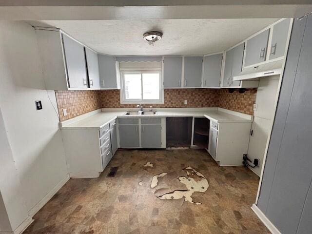 kitchen featuring gray cabinets, sink, and backsplash