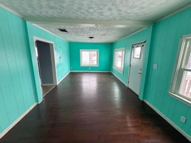 empty room featuring dark hardwood / wood-style flooring, crown molding, and a textured ceiling