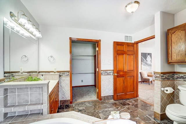 bathroom with tile walls, vanity, and toilet