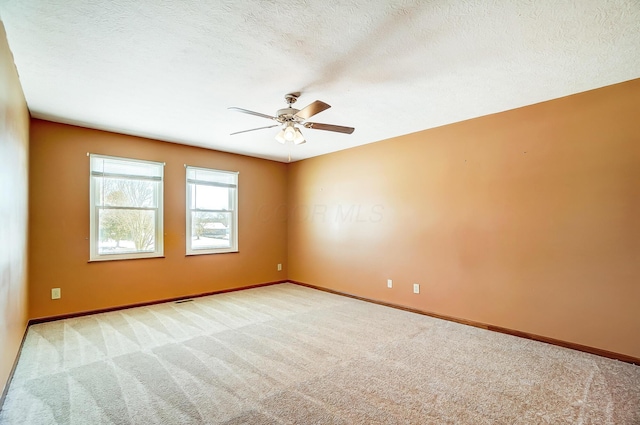 unfurnished room featuring a textured ceiling, light colored carpet, and ceiling fan