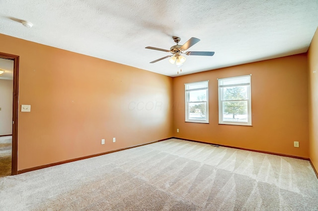 carpeted empty room with ceiling fan and a textured ceiling