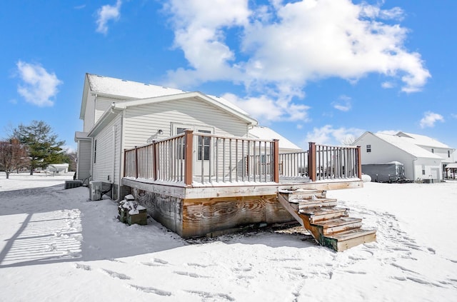 snow covered rear of property featuring central AC and a wooden deck