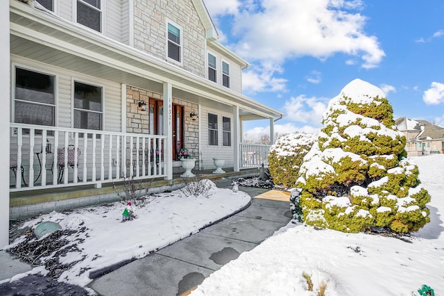 snow covered property entrance featuring a porch