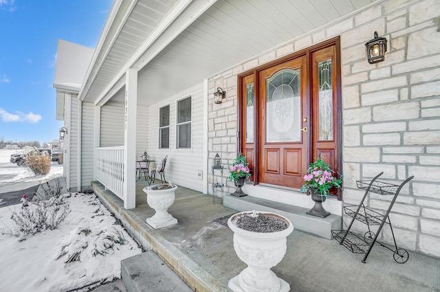 snow covered property entrance featuring covered porch