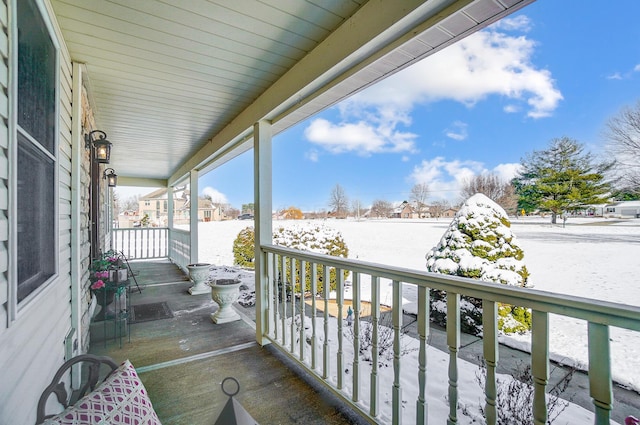 snow covered back of property with covered porch