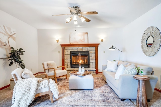 carpeted living room featuring ceiling fan and a stone fireplace