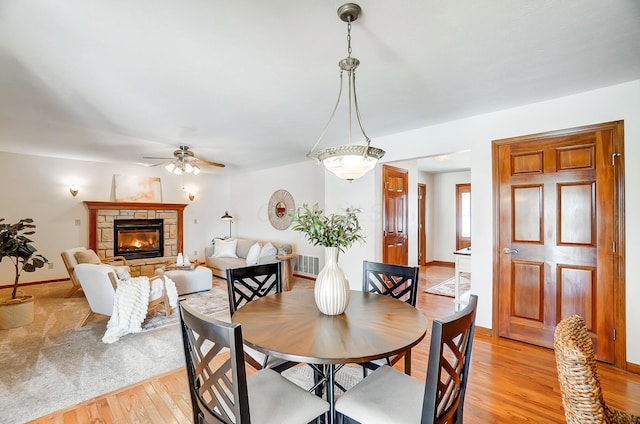 dining space featuring light hardwood / wood-style floors, ceiling fan, and a fireplace